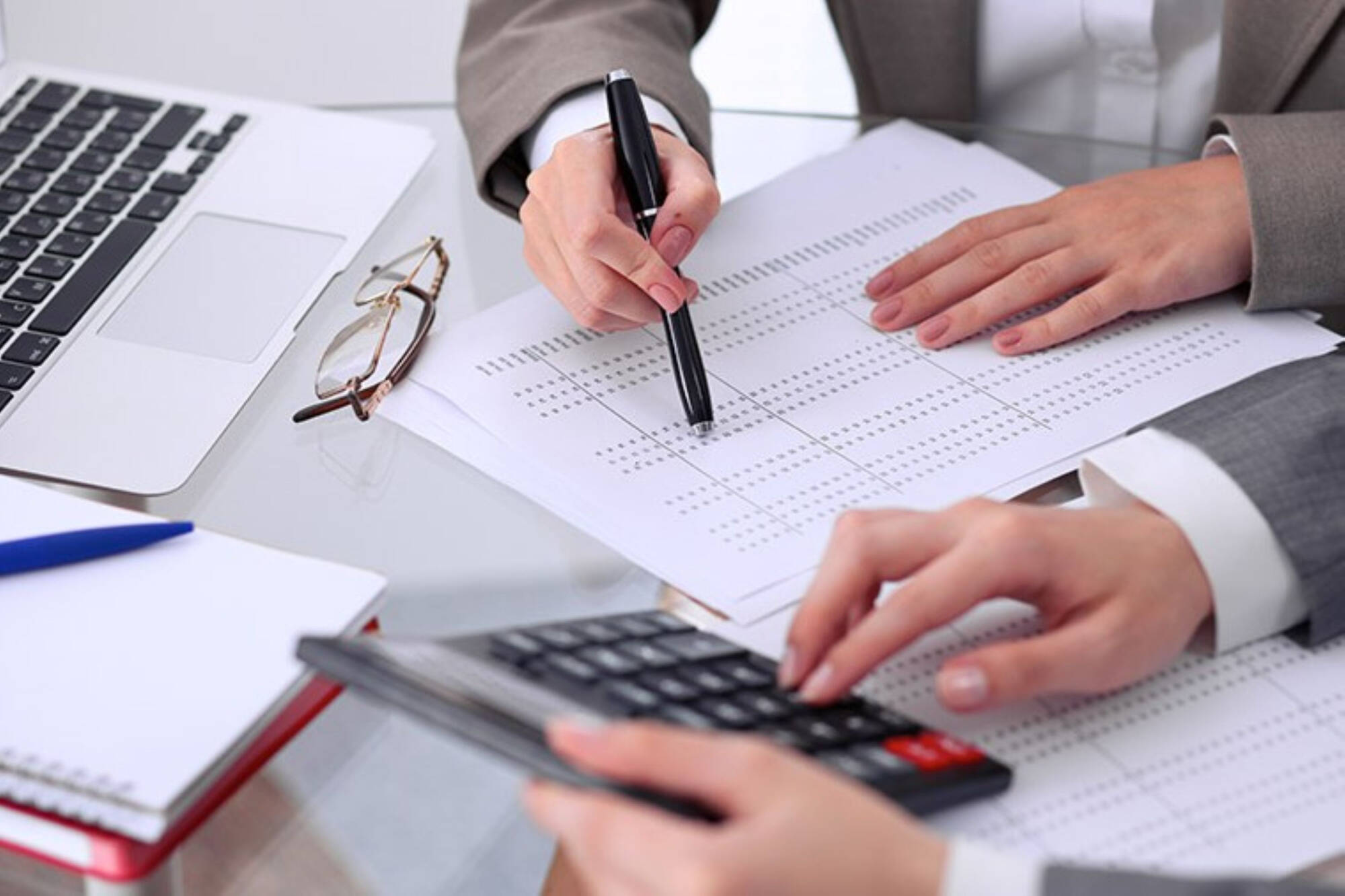 Two people working with a spreadsheet and calculator